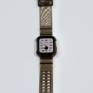 May include: A black clear watch with a black clear band. The watch face has Roman numerals and says "TUE 12".
