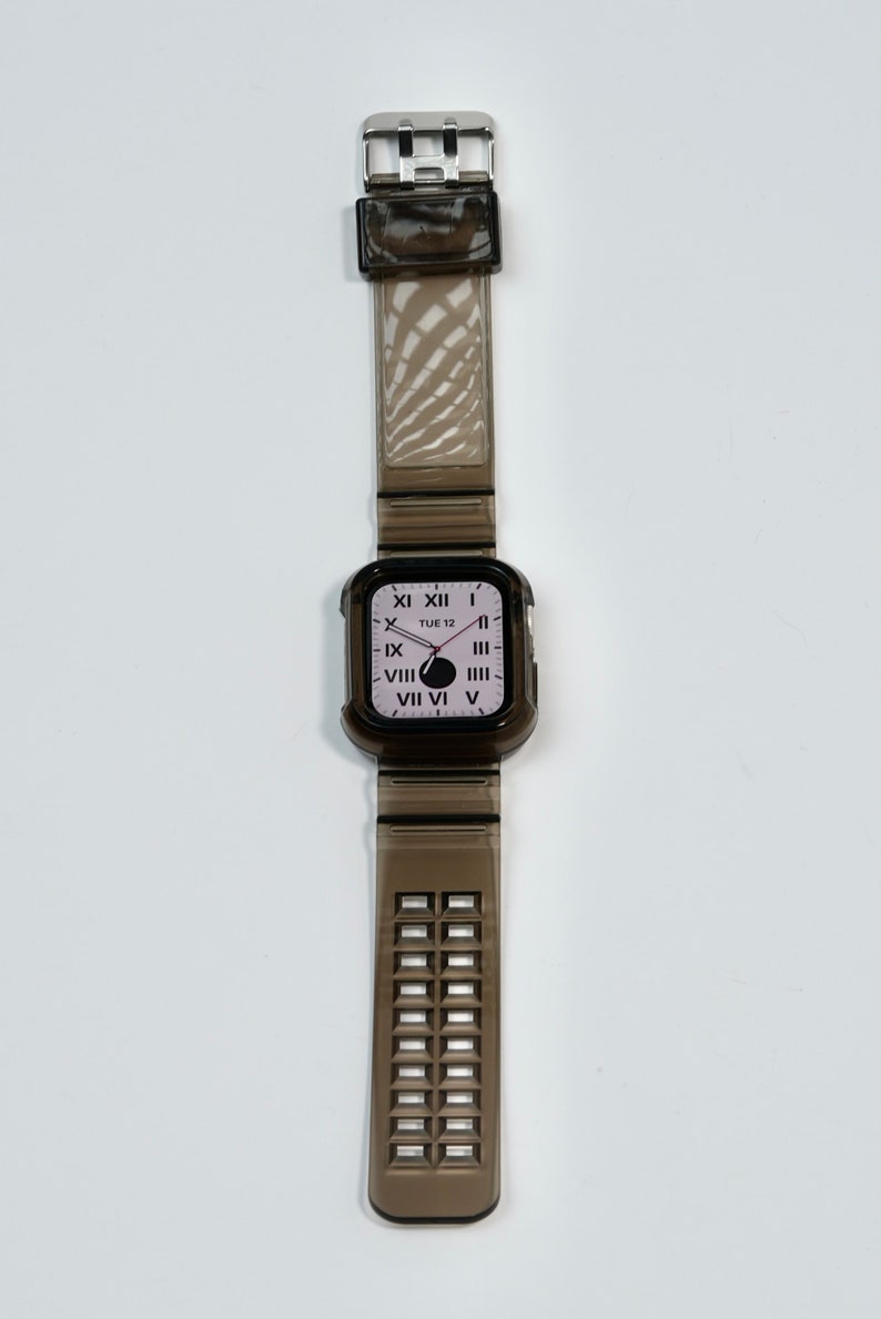 May include: A black clear watch with a black clear band. The watch face has Roman numerals and says "TUE 12".