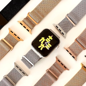 May include: A silver Apple Watch with a grey Milanese loop band. The watch face displays a yellow Chinese character. The watch is surrounded by other Milanese loop bands in gold, rose gold, and black.