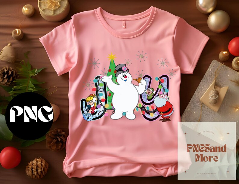 May include: Pink t-shirt with a snowman, a Christmas tree, and lights that spell out "Joy".