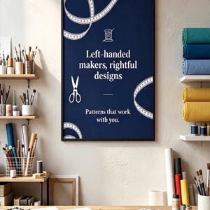 May include: A rectangular wall poster with a dark blue background, white text reading "Left-handed makers, rightful designs" and "Patterns that work with you," featuring white line art of a spool of thread, scissors, and measuring tapes.