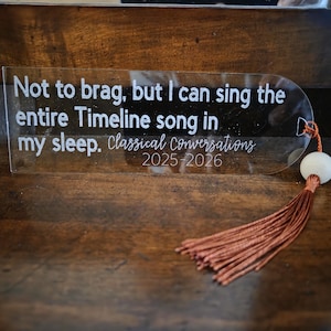 May include: Clear acrylic bookmark with the text "Not to brag, but I can sing the entire Timeline song in my sleep. Classical Conversations 2025-2026." The bookmark has a white bead and a rust-colored tassel.