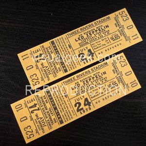 Puede incluir: Dos entradas de concierto vintage de Led Zeppelin del Three Rivers Stadium, con fecha del 24 de julio de 1973. Las entradas están amarillentas con texto negro, incluyendo el nombre de la banda, el lugar y los detalles del espectáculo. Las entradas son para Terrace Reserve, 5th Level.