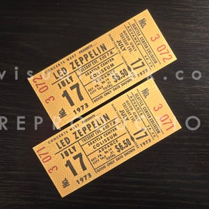 May include: Two yellow rectangular concert tickets for Led Zeppelin at the Seattle Center Coliseum on July 17, 1973. The tickets feature black text, a wavy line pattern, and the printed numbers 3 072 and 3 071 in red ink on the left and right sides.