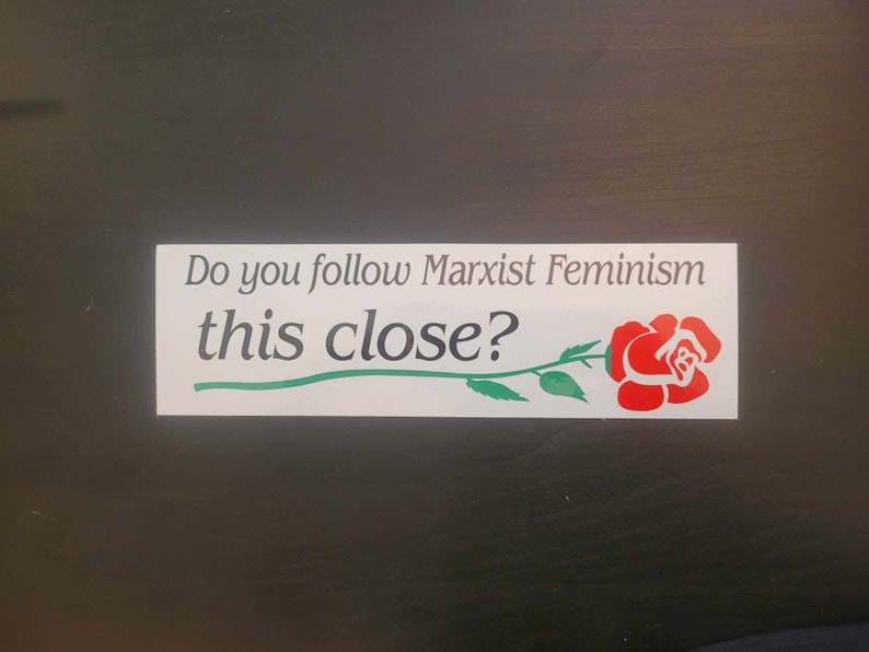 Op de afbeelding: Witte sticker met de tekst "Do you follow Marxist Feminism this close?" en een rode roos met een groene steel en bladeren.