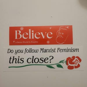 Puede incluir: Dos pegatinas rojas y blancas con un mensaje pol&iacute;tico. La pegatina superior dice "Cree" con una caricatura de un hombre con barba. La pegatina inferior dice "&iquest;Sigues el feminismo marxista tan de cerca?" con una rosa roja.