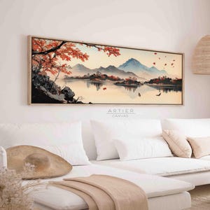 Könnte beinhalten: Ein langer, horizontaler Leinwanddruck mit einem Aquarellbild einer Bergkette, die sich in einem See spiegelt. Die Berge sind blau und violett, der See ist hellblau. Am Ufer des Sees stehen Bäume mit roten Blättern. Das Bild ist in einem hellen Holzrahmen gerahmt.