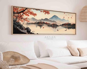 May include: A long, horizontal canvas print featuring a watercolor painting of a mountain range reflected in a lake. The mountains are blue and purple, and the lake is a light blue. There are trees with red leaves on the shore of the lake. The painting is framed in a light wood frame.