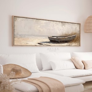 Puede incluir: Una pintura de lienzo larga y horizontal de un barco de madera desgastado en una playa de arena. El barco es gris y tiene un aspecto desgastado y desgastado. La playa es de color marrón claro y el agua es de color azul claro. El cielo es de color gris claro con algunas nubes. La pintura tiene un aspecto vintage y rústico.