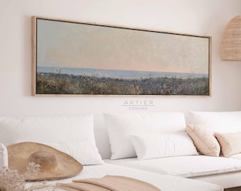 Puede incluir: Una pintura de lienzo larga y horizontal que representa un paisaje marítimo con un campo de flores silvestres en primer plano. El cielo es de un suave azul pálido con toques de rosa y morado. El mar es de un azul claro tranquilo. La pintura está enmarcada en un marco de madera natural.