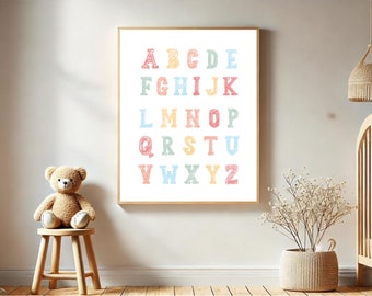 May include: A framed alphabet print with colorful letters in a nursery setting. The letters are drawn in a hand-drawn style with a light blue, pink, yellow, and orange color scheme.