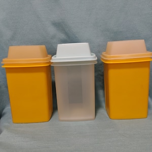 Könnte beinhalten: Drei Plastikbehälter mit Deckeln. Zwei sind gelb und einer ist durchscheinend weiß.