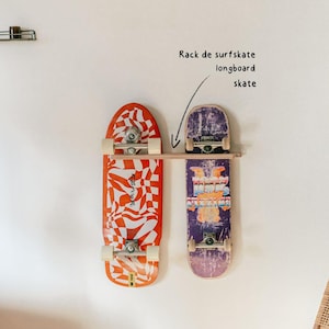 Può includere: Due skateboard montati su un muro bianco. Uno è rosso e bianco con un motivo ondulato, l'altro è viola con un design grafico. Sono montati su una mensola di legno.