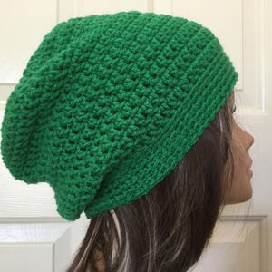 May include: A green crocheted beanie hat. The hat is slouchy and has a simple stitch pattern.