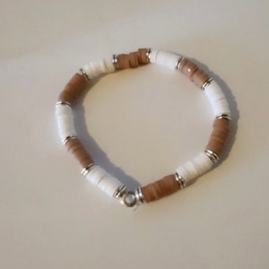 Peut inclure: Un bracelet en perles brunes et blanches avec des accents argentés.