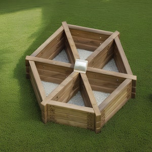 May include: A hexagonal wooden raised garden bed with six triangular sections. The bed is made of light brown wood and filled with small white stones. It sits on a green lawn.