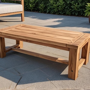 May include: A rectangular wooden coffee table with a natural wood finish. The table has a simple design with a wide, flat top and a sturdy base.
