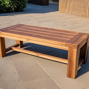 May include: A wooden bench with a natural brown finish. The bench has a rectangular top and a simple, sturdy design.