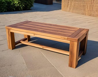 May include: A wooden bench with a natural brown finish. The bench has a rectangular top and a simple, sturdy design.