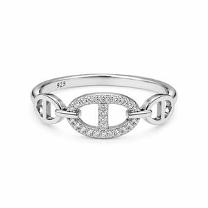 May include: A silver-toned ring featuring a central oval link motif embellished with small clear stones. The band is polished and includes a 925 hallmark stamp on the inner surface, indicating sterling silver composition for this jewelry piece.