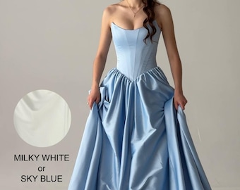 May include: A strapless sky blue gown with a corset-style bodice and a full, pleated floor-length skirt. The dress features a sweetheart neckline and a smooth, satin-like finish. Text on the image reads: MILKY WHITE or SKY BLUE.