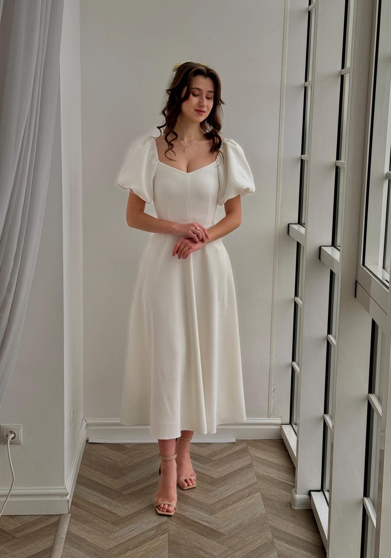 May include: A white midi dress with a square neckline and puff sleeves.