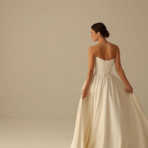 Bride wearing satin wedding dress with detachable sleeves and strapless corset top