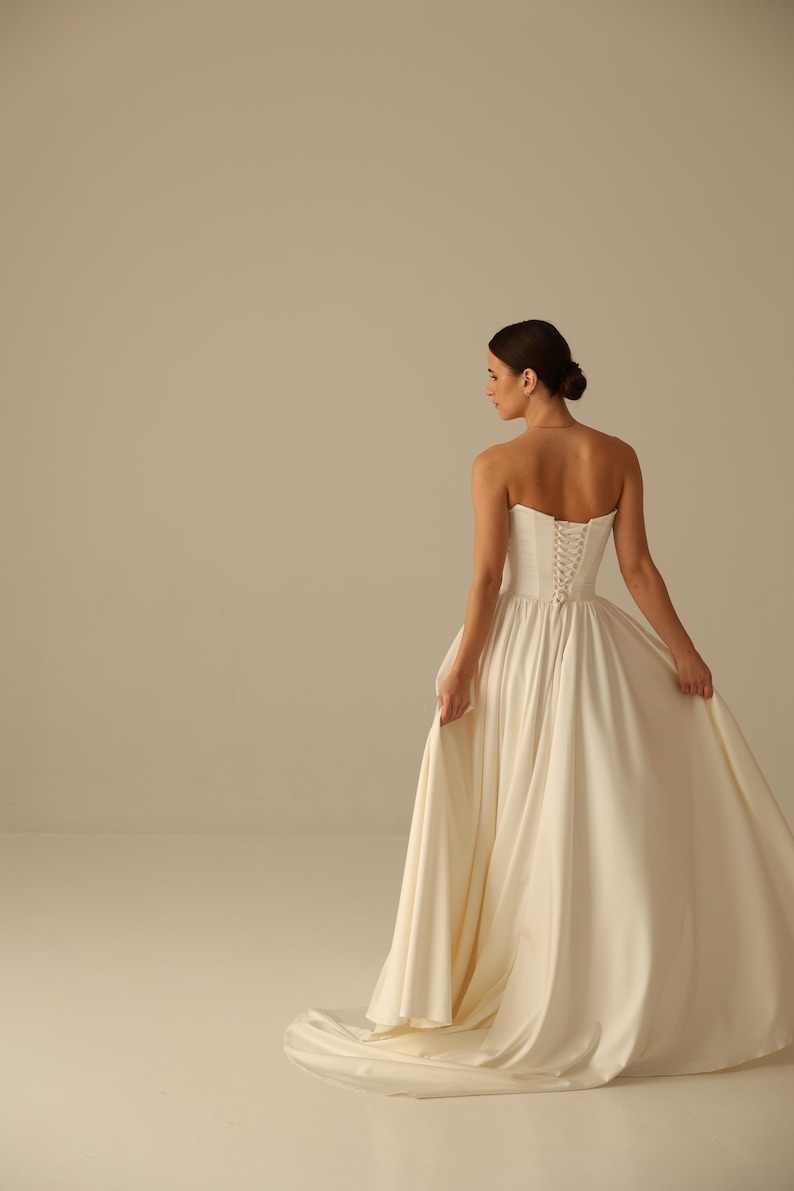 Bride wearing satin wedding dress with detachable sleeves and strapless corset top