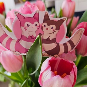 May include: Two pink and brown cartoon animal stickers with white stripes on a bouquet of pink tulips.