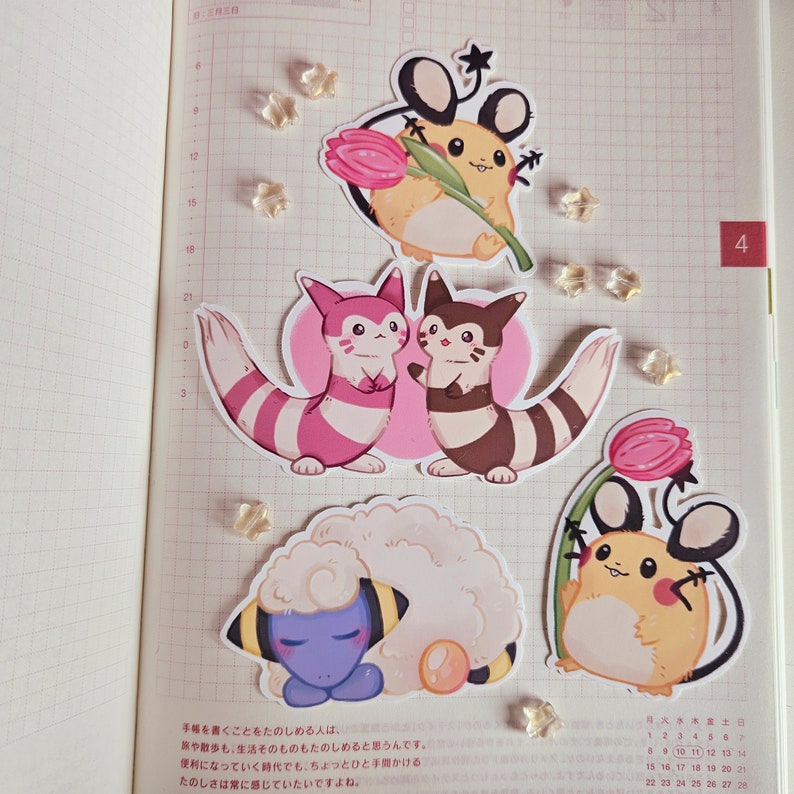 May include: A set of six illustrated stickers featuring cartoon characters from the Pokemon franchise. The stickers are printed on white paper with a glossy finish. The characters include a pink and white Eevee, a brown and white Eevee, a yellow Pikachu, a brown and white Vaporeon, a blue and white Snorlax, and a yellow and brown Pichu.