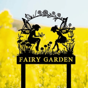 May include: Black metal silhouette of two fairies with wings, sitting on a flower-filled garden arch, with the text "FAIRY GARDEN" below.