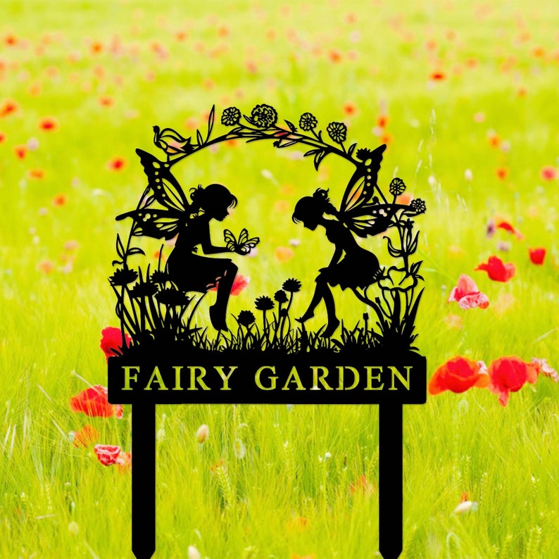 May include: Black metal silhouette of two fairies with wings, sitting on a flower-covered arch with the text "FAIRY GARDEN" on a sign below.