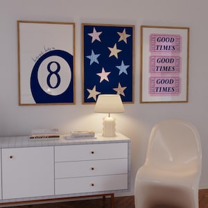 Op de afbeelding: Drie ingelijste kunstdrukken. Eén heeft een marineblauwe achtbal met de tekst "lucky girl, lucky me". Een andere heeft een marineblauwe achtergrond met stervormen. De derde print zegt "GOOD TIMES".