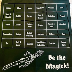 May include: A black divination cloth with white text and graphics. The cloth features a grid of words like "Spiritual" and "Success." A stylized wand graphic and the words "Be the Magick!" are at the bottom.
