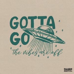 May include: A graphic design on a light tan background featuring a dark green UFO with a beam of light shining downward. The text reads "GOTTA GO" in bold block letters and "The vibes are off" in a cursive script, surrounded by small star icons.
