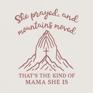 Peut inclure: Graphique beige avec le texte "She prayed, and mountains moved" en écriture cursive. En dessous, le texte "THAT'S THE KIND OF MAMA SHE IS" est en sans-serif. L'image présente un design de montagne avec des mains en prière et une croix.