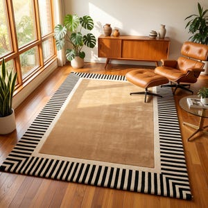 May include: A rectangular area rug with a beige center and a border of black and white stripes. The rug is placed on a hardwood floor in a living room setting, with a leather chair and wooden cabinet visible in the background.