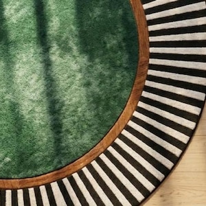 Puede incluir: Una alfombra redonda con un centro verde, un borde marr&oacute;n y un borde exterior a rayas blancas y negras. El dise&ntilde;o de la alfombra presenta una combinaci&oacute;n de texturas y patrones, creando un revestimiento de suelo visualmente atractivo.