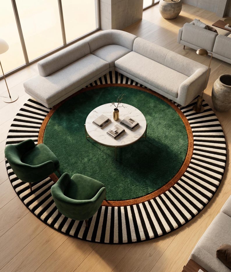 Puede incluir: Un interior de sal&oacute;n moderno con un sof&aacute; esquinero gris claro cerca de una ventana. Una alfombra redonda con centro verde, borde marr&oacute;n y borde a rayas blancas y negras es el punto focal. Dos sillones de terciopelo verde y una mesa de centro de m&aacute;rmol completan la escena.