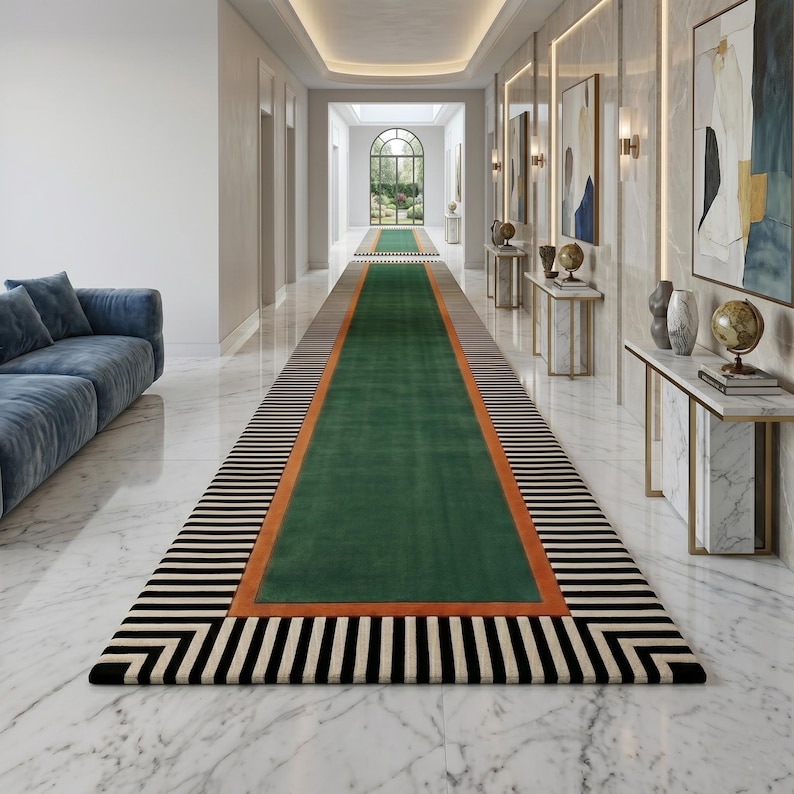 Puede incluir: Una alfombra larga y rectangular para pasillo con un dise&ntilde;o llamativo. La alfombra presenta una secci&oacute;n central verde bordeada por una franja naranja, una franja marr&oacute;n y un patr&oacute;n de rayas blancas y negras. La alfombra est&aacute; colocada en un pasillo largo con suelo de m&aacute;rmol.