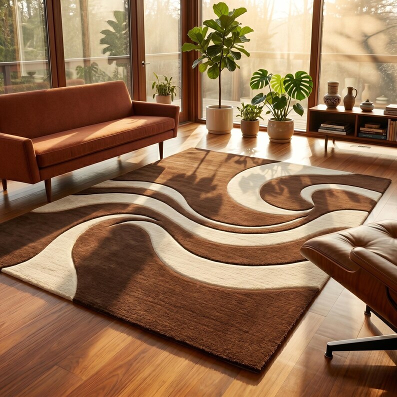 May include: A brown and beige area rug with a wavy design. The rug is rectangular and features a pattern of flowing lines in shades of brown and cream. The rug is placed in a living room with a brown sofa, plants, and a leather chair.