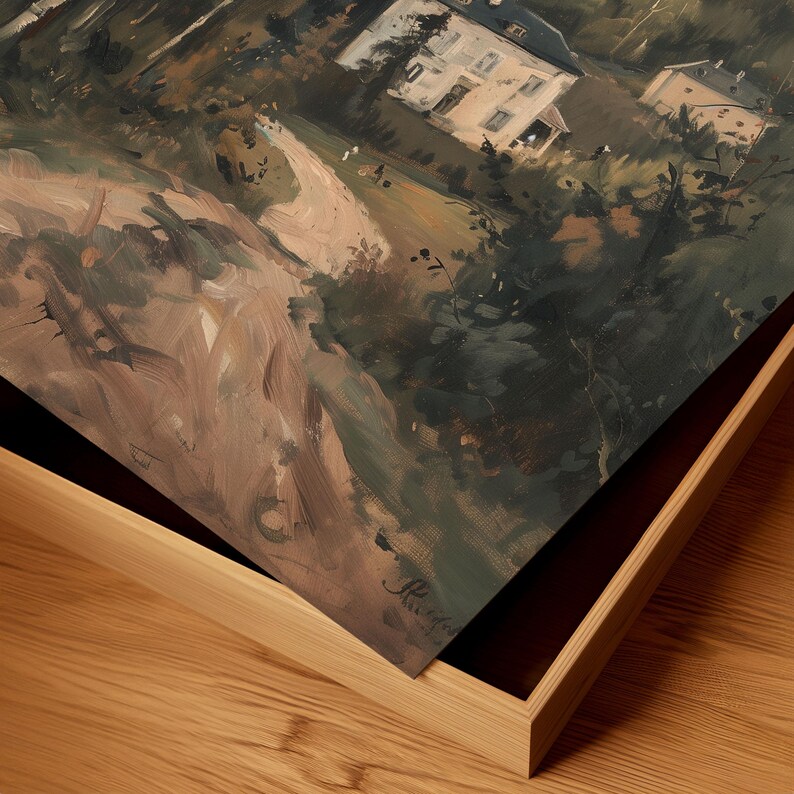 May include: An oil painting depicting a landscape with buildings, trees, and a winding road. The artwork is framed in a light-colored wooden frame. The painting's color palette includes shades of brown, green, and white, creating a serene and naturalistic scene.