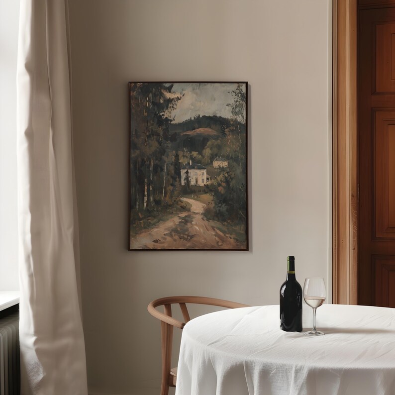May include: An oil painting in a dark wooden frame depicts a road leading to a white house nestled in a forest. A bottle of wine and a wine glass sit on a white tablecloth. A wooden chair is in the foreground.