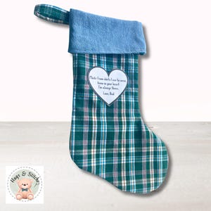 May include: A Christmas stocking made from green, white, and blue plaid fabric with a solid light blue cuff and hanging loop. A white heart-shaped patch is sewn on the front with the text: Made from shirts I use to wear, know in your heart I'm always there. Love, Dad.