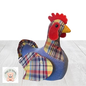 May include: A fabric chicken figurine featuring a blue body and a multi-colored plaid pattern on the wings, tail, and neck. It has a bright red felt comb and wattle, a yellow beak, and a small white button detail on the wing. The logo Hugs & Stitches is visible.