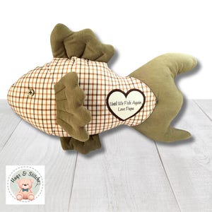 May include: A brown and tan plaid fish-shaped plush toy with green felt fins and a heart-shaped patch that reads "Until We Fish Again Love Papa".