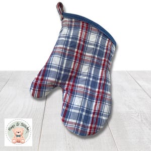 May include: Red, white, and blue plaid oven mitt with a blue denim trim. The mitt is quilted and has a loop for hanging.