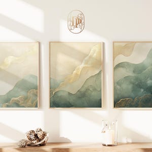 Könnte beinhalten: Drei gerahmte abstrakte Kunstdrucke mit einem Aquarelldesign in Grün und Gold. Die Drucke zeigen ein fließendes, organisches Muster in Grüntönen und Gold.