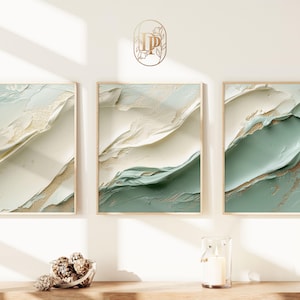 Op de afbeelding: Drie ingelijste abstracte kunstprints met een groen-wit kleurenschema. De prints hebben een textuur, gelaagde look met gouden accenten.