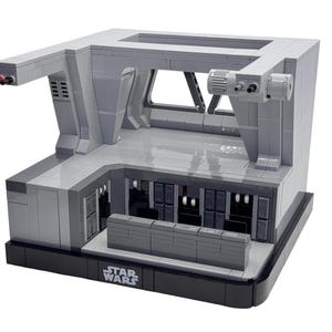 Könnte beinhalten: Ein graues Lego Star Wars Modell eines Raumschiff-Innenraums mit einem Bedienfeld, einem Fenster und einem Star Wars Logo auf der Basis.